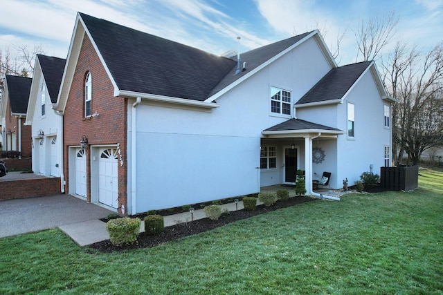 traditional-style home featuring an attached garage, a front yard, aphalt driveway, and brick siding