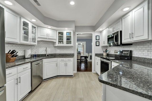 kitchen with stainless steel appliances, white cabinets, a sink, and light wood-style flooring