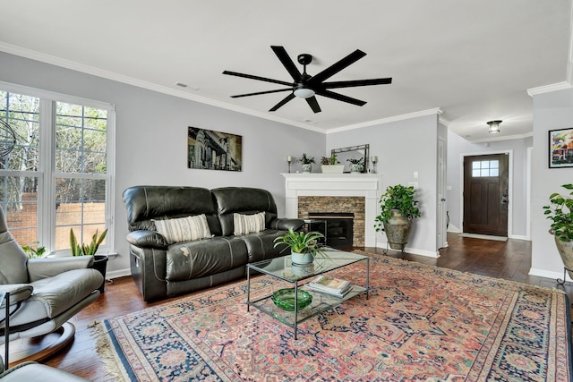 living room with baseboards, visible vents, ornamental molding, wood finished floors, and a stone fireplace