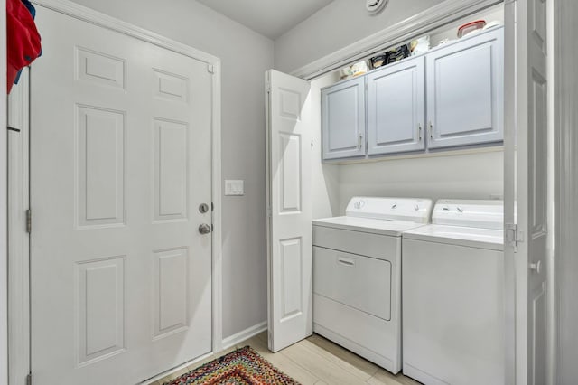 clothes washing area featuring light wood-style flooring, cabinet space, washer and clothes dryer, and baseboards