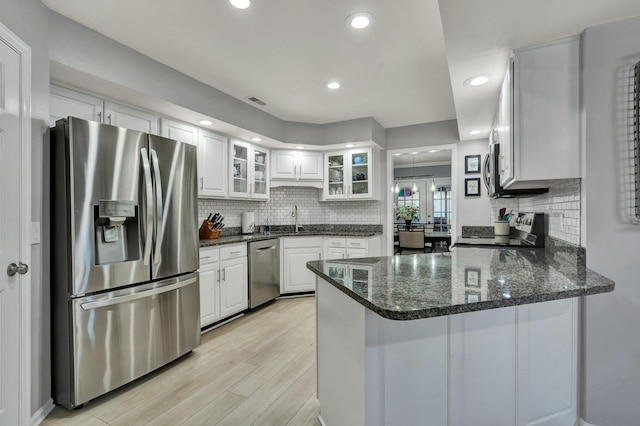 kitchen featuring stainless steel appliances, glass insert cabinets, white cabinets, a sink, and a peninsula