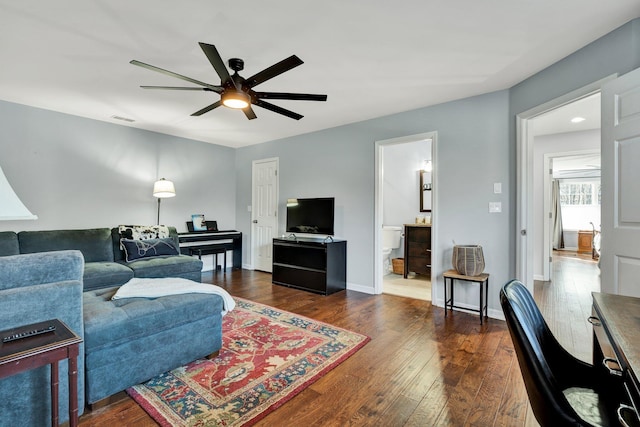 living area with dark wood-type flooring, visible vents, baseboards, and a ceiling fan