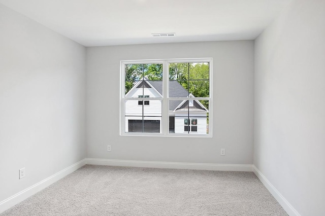 spare room featuring carpet floors, visible vents, and baseboards