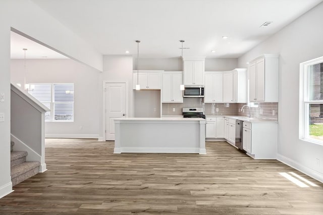 kitchen with tasteful backsplash, visible vents, appliances with stainless steel finishes, light wood-style floors, and a sink