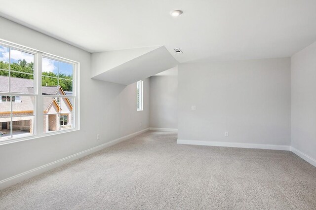 additional living space with baseboards, visible vents, and light colored carpet