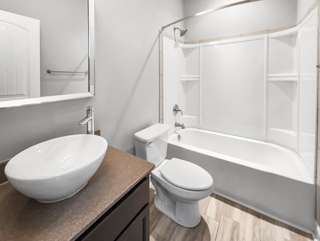 bathroom featuring toilet,  shower combination, wood finished floors, and vanity