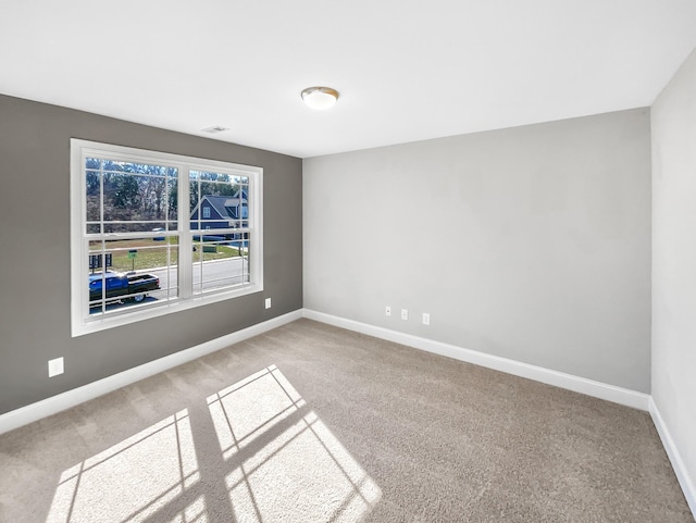 spare room featuring visible vents, baseboards, and carpet flooring