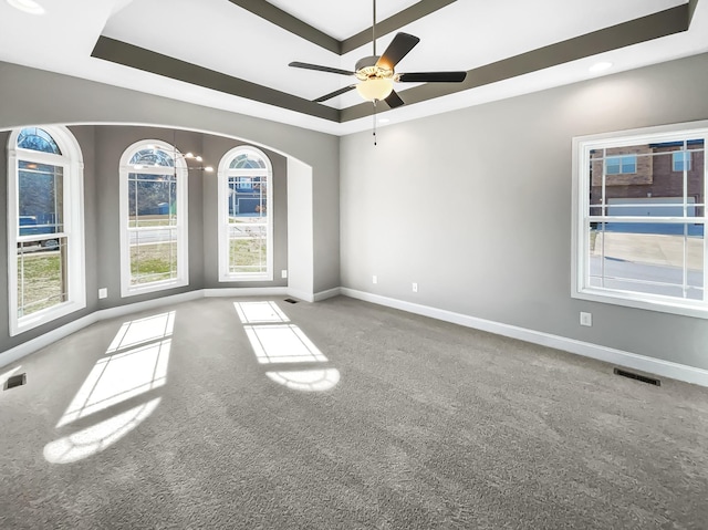 empty room with carpet flooring, a raised ceiling, a ceiling fan, and baseboards