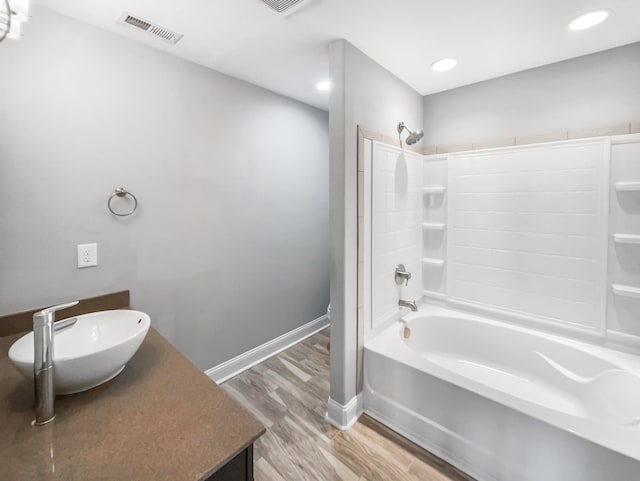 bathroom with wood finished floors, vanity, visible vents, baseboards, and tub / shower combination