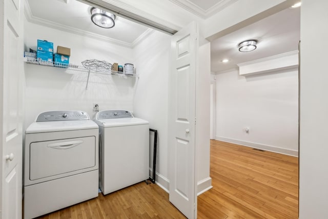 washroom with light wood-type flooring, laundry area, washer and clothes dryer, and crown molding