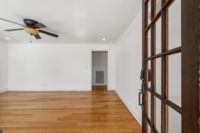 empty room with light wood-style floors, ceiling fan, baseboards, and crown molding