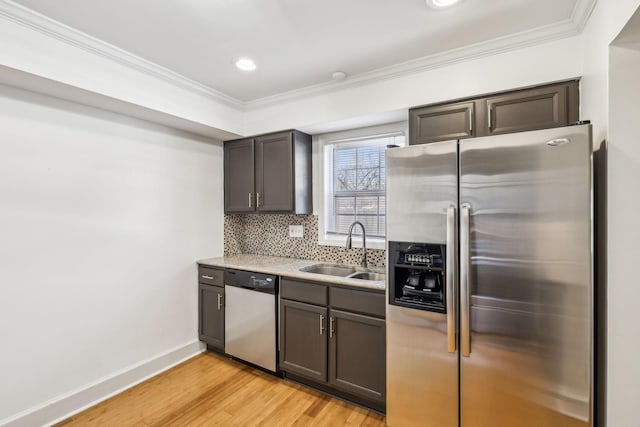 kitchen with tasteful backsplash, appliances with stainless steel finishes, a sink, and ornamental molding