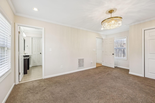 unfurnished bedroom with carpet, visible vents, ornamental molding, a chandelier, and baseboards