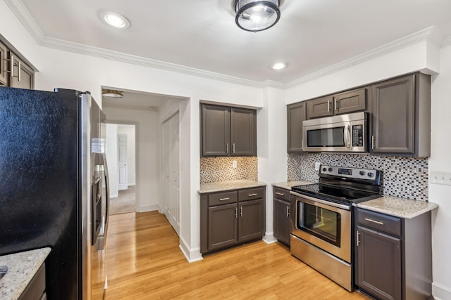 kitchen featuring appliances with stainless steel finishes, ornamental molding, light wood finished floors, and tasteful backsplash