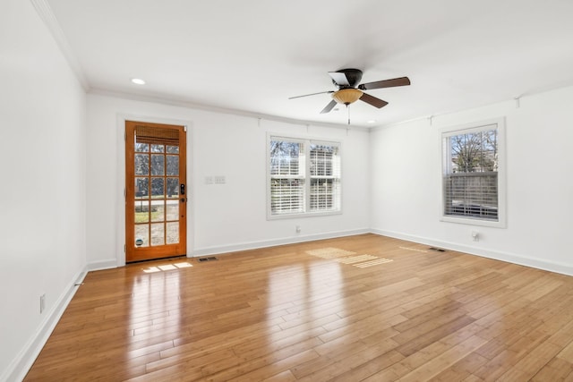 spare room featuring a ceiling fan, baseboards, visible vents, light wood-style floors, and crown molding