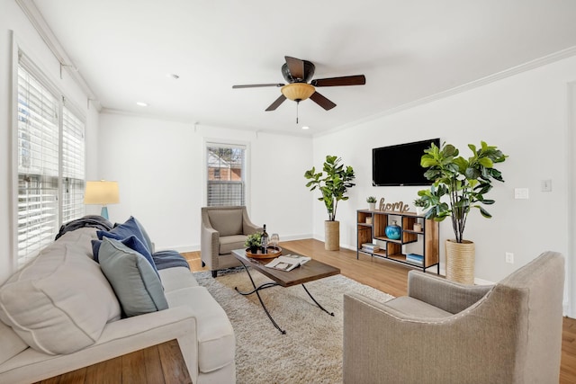 living area featuring a healthy amount of sunlight, ornamental molding, and wood finished floors