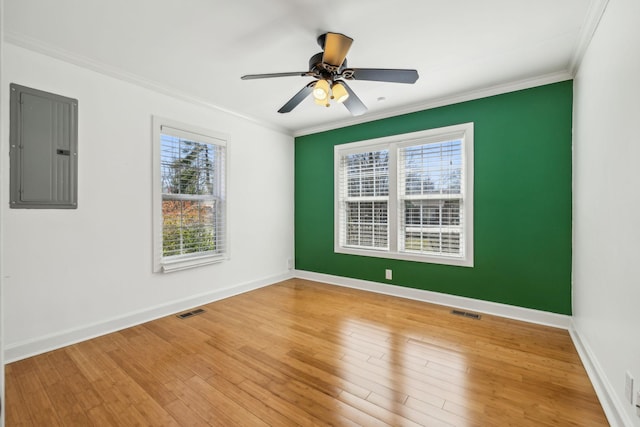 spare room with visible vents, wood finished floors, electric panel, and crown molding