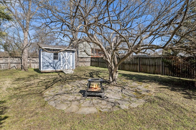 view of yard with a storage shed, a fenced backyard, a fire pit, and an outdoor structure