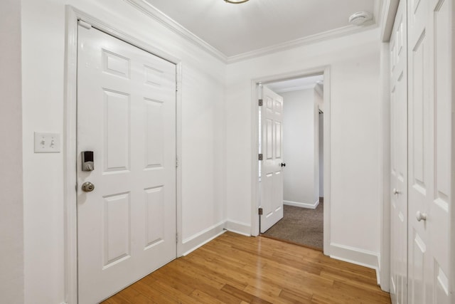 entryway with light wood-style floors, crown molding, and baseboards