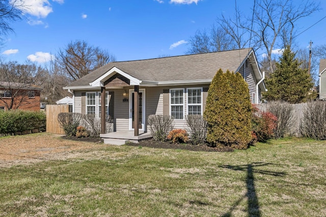 view of front facade featuring roof with shingles, fence, and a front lawn