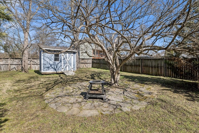 view of yard with a storage shed, a fenced backyard, a fire pit, and an outbuilding