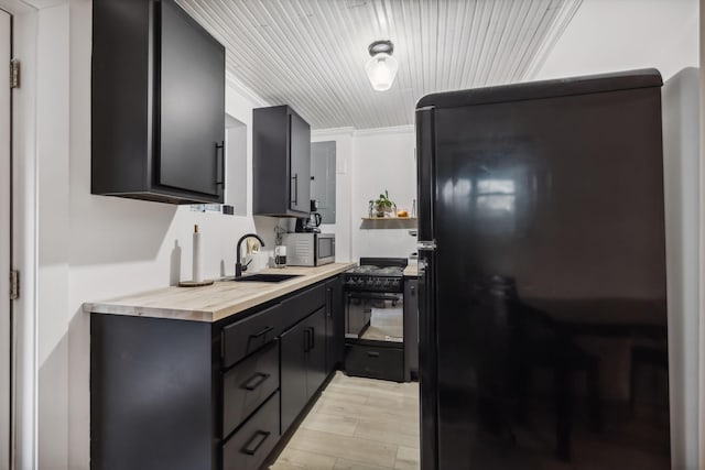 kitchen with light wood finished floors, wood counters, dark cabinets, black appliances, and a sink