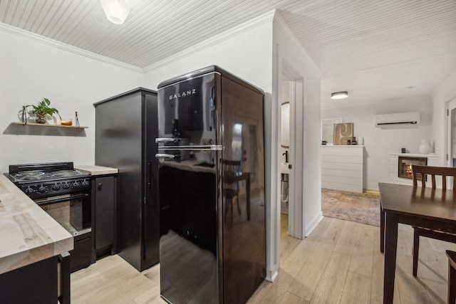 kitchen featuring light countertops, a wall mounted AC, light wood-type flooring, black appliances, and crown molding