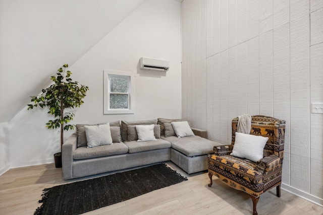 living area featuring high vaulted ceiling, a wall mounted AC, wood finished floors, and baseboards