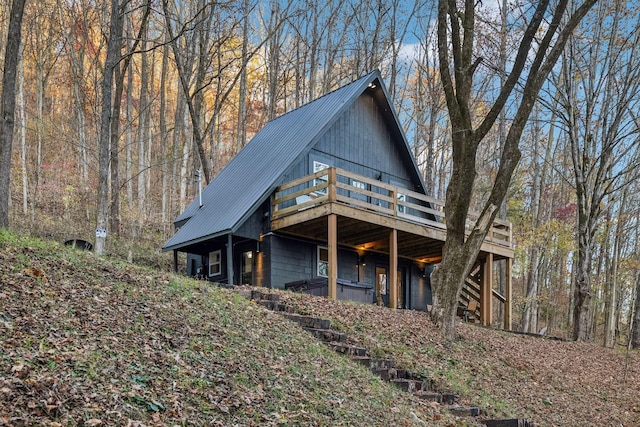 exterior space featuring a forest view, metal roof, and a wooden deck