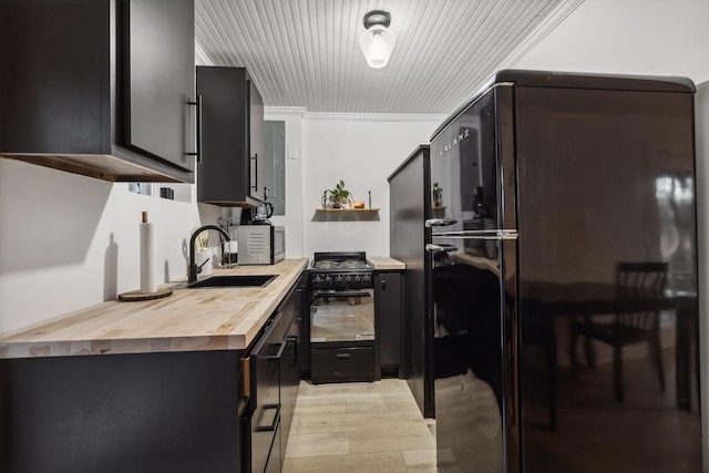 kitchen featuring butcher block counters, dark cabinetry, a sink, and black appliances