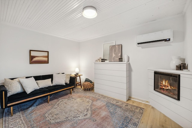 living area with ornamental molding, a glass covered fireplace, light wood finished floors, and a wall mounted AC