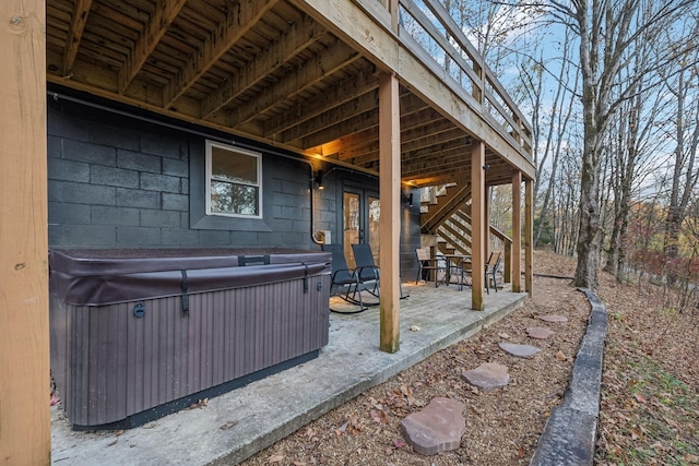 view of patio with a hot tub and stairs