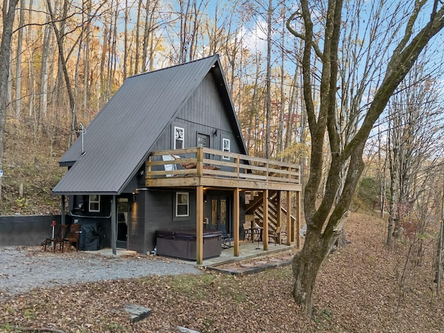 view of front of house with a hot tub, a patio area, metal roof, a wooden deck, and stairs