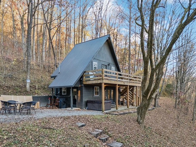 rear view of property with a deck, metal roof, stairway, and a hot tub