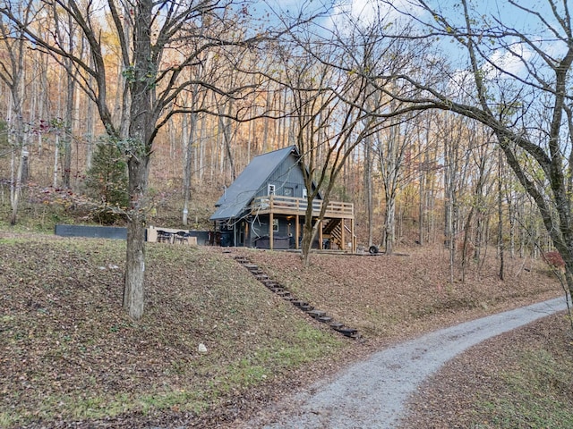 exterior space featuring a view of trees, stairway, and a wooden deck