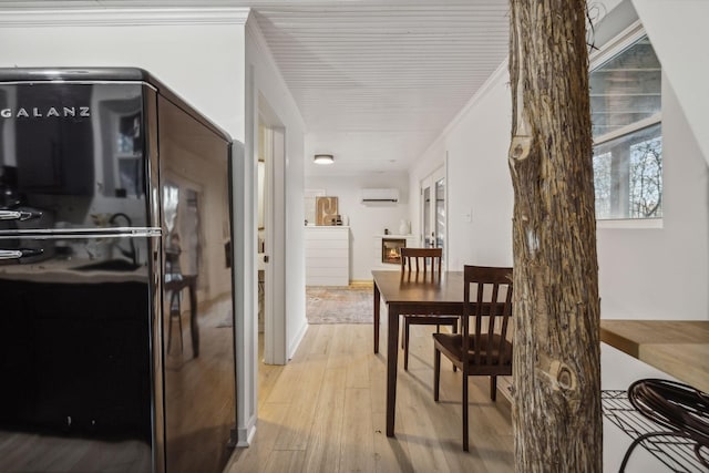 kitchen featuring ornamental molding, light wood-style flooring, a wall mounted AC, and freestanding refrigerator