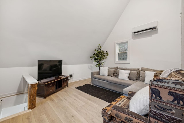 living area with lofted ceiling, a wall mounted AC, light wood-type flooring, and baseboards