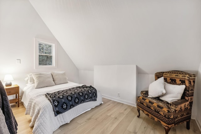 bedroom featuring vaulted ceiling, light wood finished floors, and baseboards