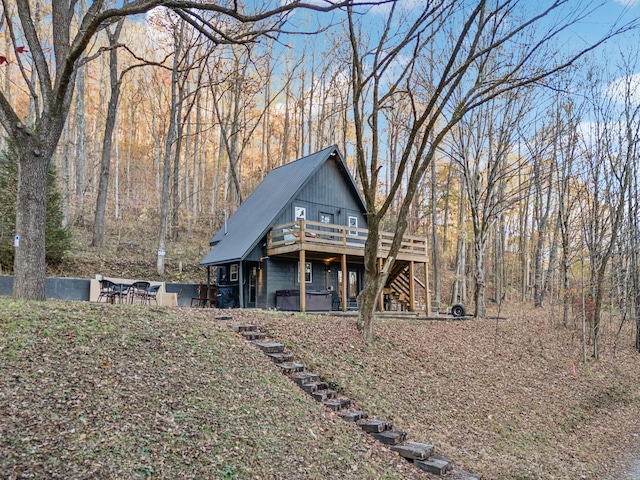 view of front facade with stairs, a forest view, and a wooden deck