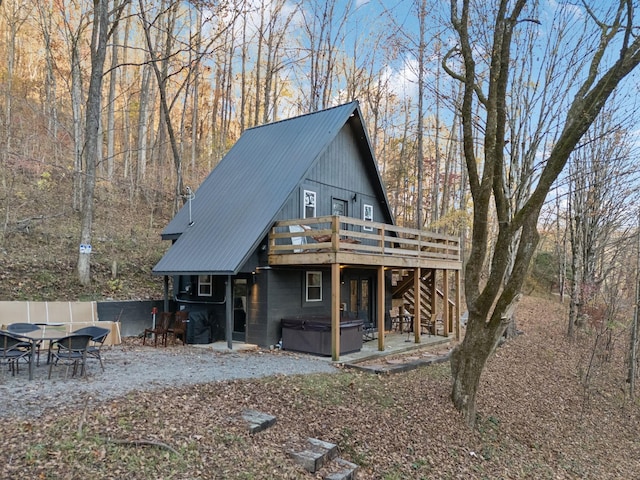 back of house with stairs, metal roof, a wooden deck, and a hot tub