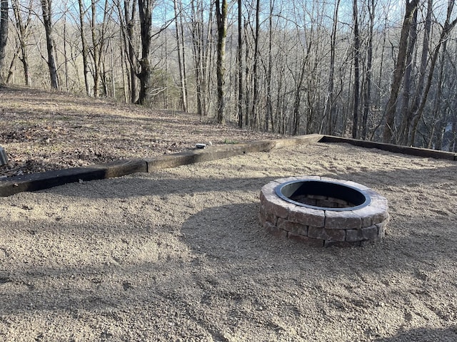 view of yard featuring a fire pit and a view of trees