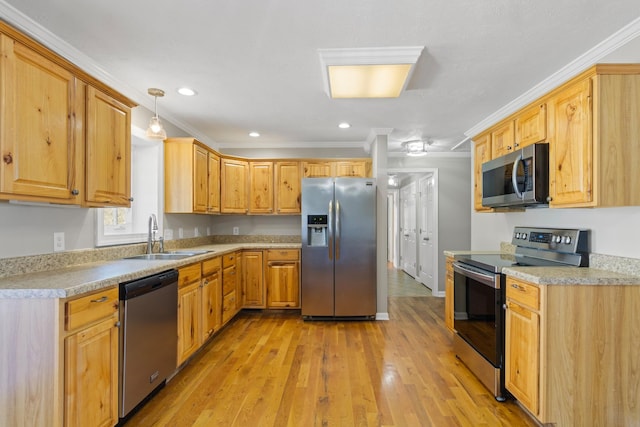 kitchen featuring appliances with stainless steel finishes, light countertops, a sink, and ornamental molding