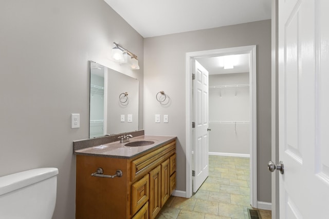 bathroom featuring toilet, vanity, visible vents, and baseboards