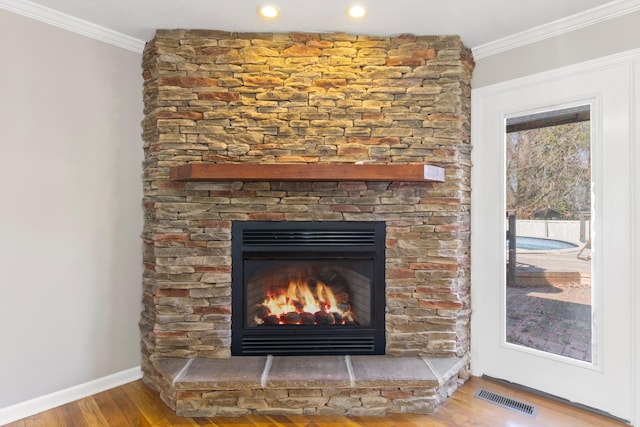 interior details with a fireplace, visible vents, crown molding, and wood finished floors