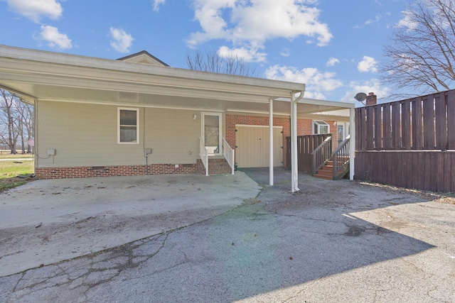 back of house featuring an attached carport, crawl space, driveway, and entry steps