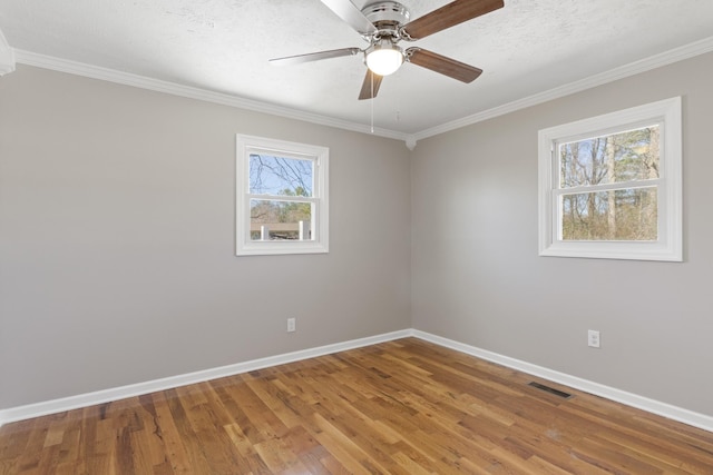 unfurnished room featuring crown molding, visible vents, a textured ceiling, wood finished floors, and baseboards