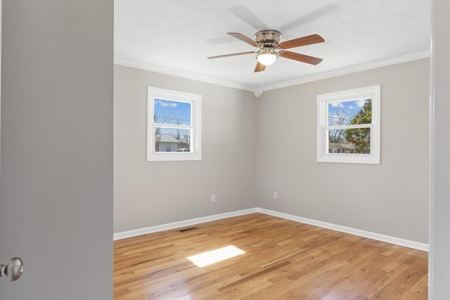 unfurnished room featuring ornamental molding, light wood-style flooring, a wealth of natural light, and baseboards