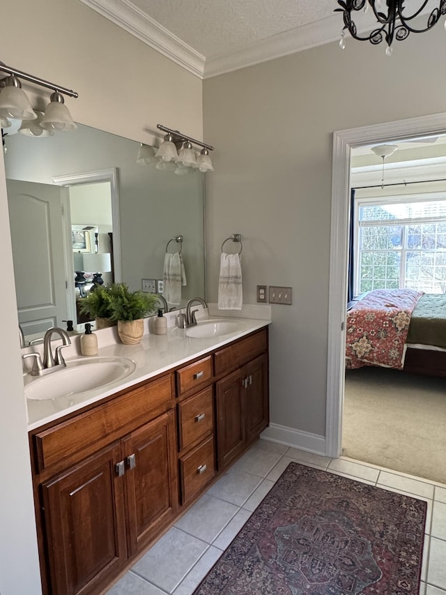 ensuite bathroom featuring a sink, connected bathroom, crown molding, and tile patterned floors