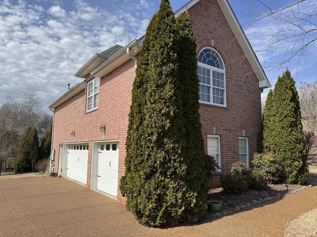 view of side of home featuring brick siding, concrete driveway, and an attached garage