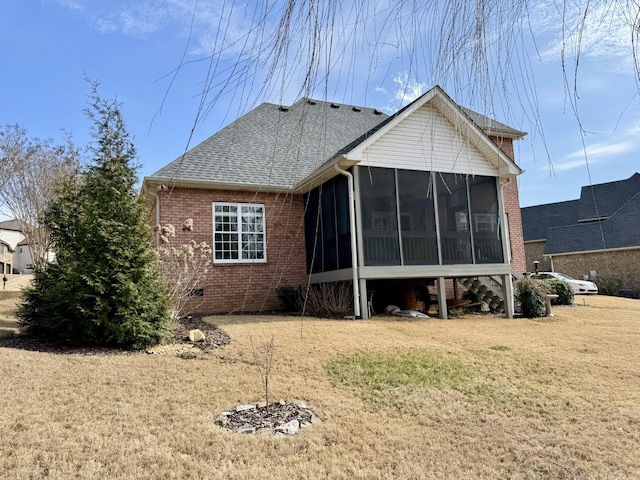 back of property with brick siding, a lawn, roof with shingles, and a sunroom